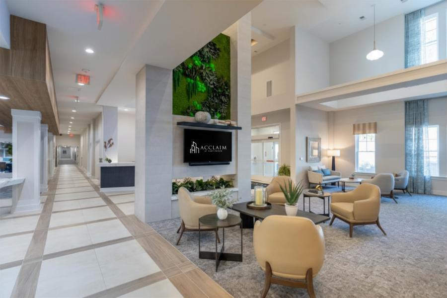 Attain on 5th apartment homes with Modern lobby with beige chairs, greenery wall, and natural light; "Acclaim" sign on display.