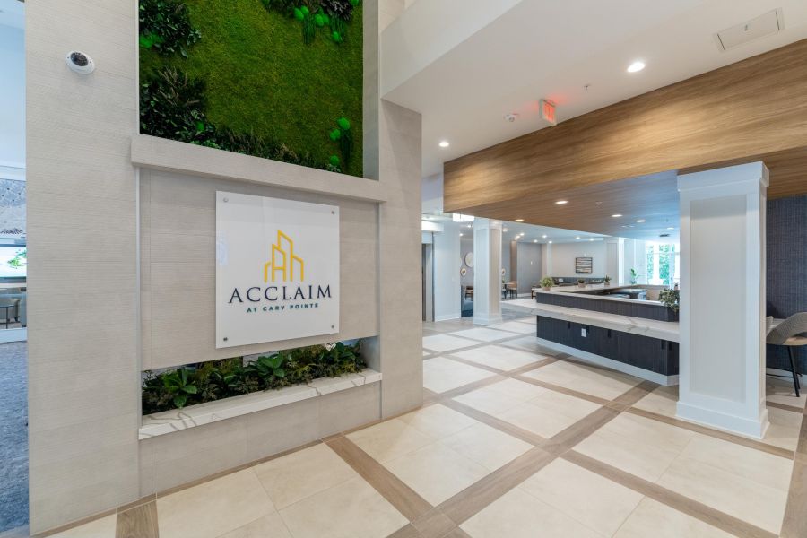 Acclaim at Cary Pointe apartment homes with Modern lobby with Acclaim at Cary Pointe sign, green wall, tiled floor, and wooden ceiling accents.