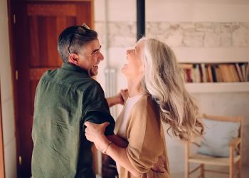 Acclaim at Cary Pointe apartment homes with An older couple dances and laughs together in a cozy, sunlit living room.