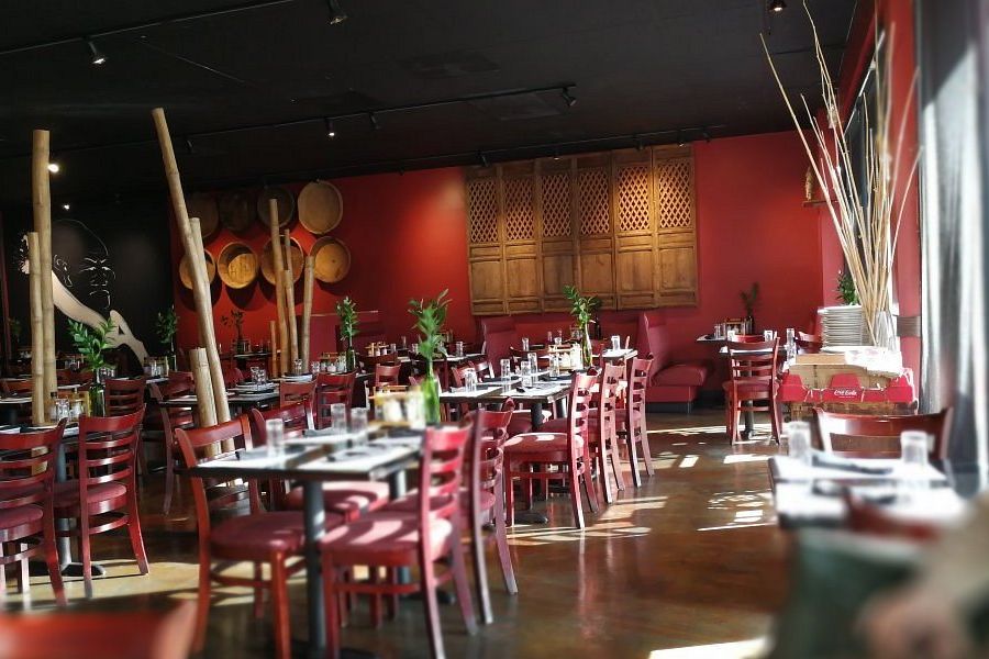 Acclaim at Cary Pointe apartment homes with A sunlit, modern restaurant with red chairs, set tables, and Asian-inspired decor.