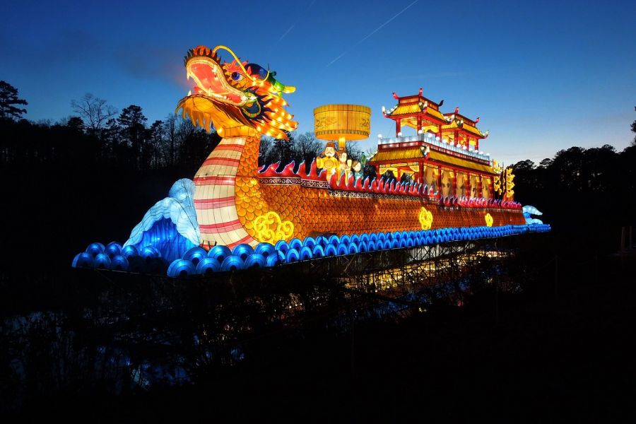 Acclaim at Cary Pointe apartment homes with A brightly lit dragon boat lantern floats on water at dusk, glowing with colorful lights.