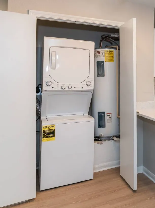 Acclaim at Cary Pointe apartment homes with Stacked washer and dryer next to two water heaters inside a closet with open doors.