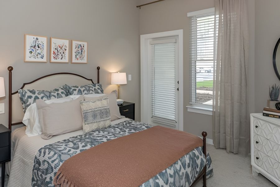 Acclaim at Cary Pointe apartment homes with A neatly made bed with patterned bedding in a bright, modern bedroom with gray walls and large windows.