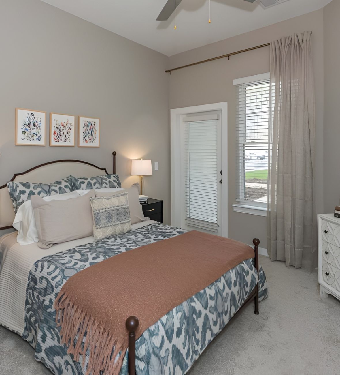 Acclaim at Cary Pointe apartment homes with A neatly made bed with patterned bedding in a bright, modern bedroom with gray walls and large windows.